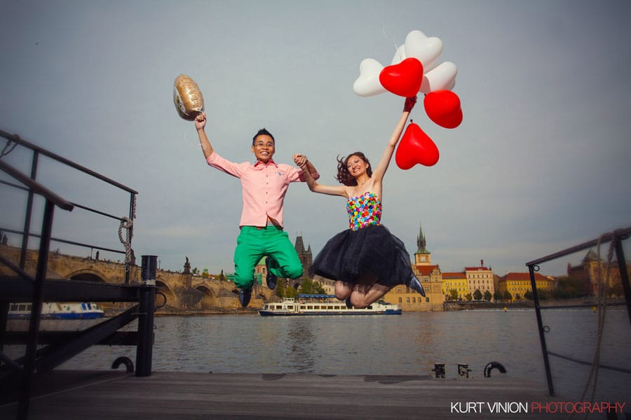designer dress, red & white balloons, couple jumping in air, Charles Bridge, Prague