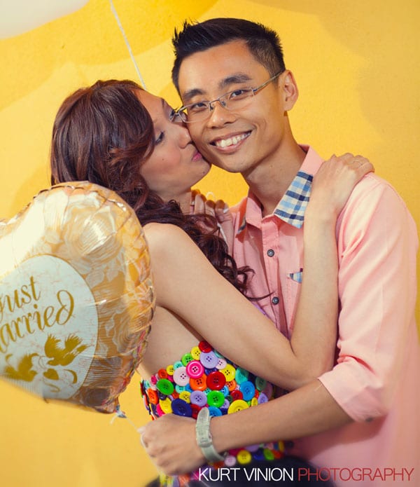 good looking couple, just married balloon, designer clothes, smiling man, kissing girl, yellow wall