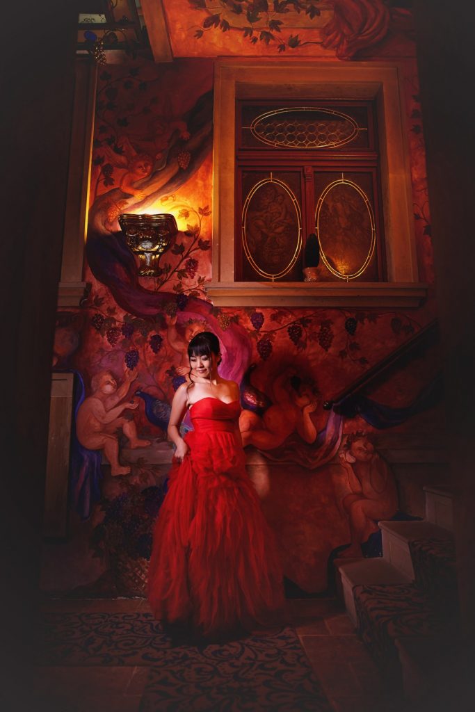 Prague, interior portrait, woman wearing red dress, painted walls, angels, modern portrait