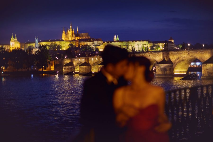 Prague, Charles Bridge at night, Prague Castle in background, couple embracing foreground 