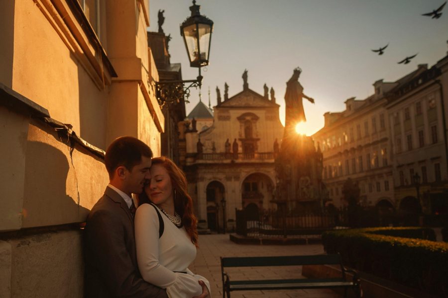 Prague, well dressed couple embracing, love locks, sun flare, statue 