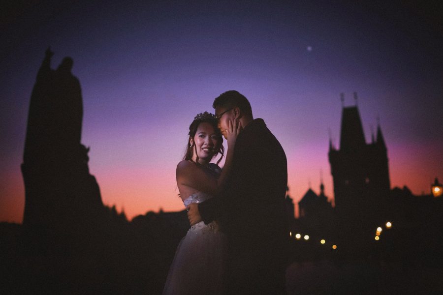 Charles Bridge at night, couple embracing, wedding dress, blue & pink sky, gas lamps