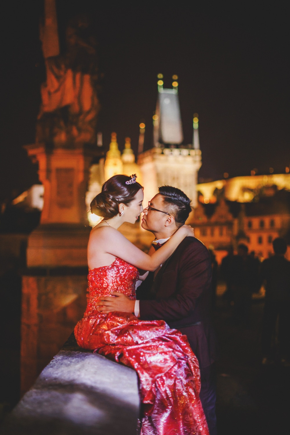 Prague Charles Bridge, young couple, red dress, embracing, night time photo
